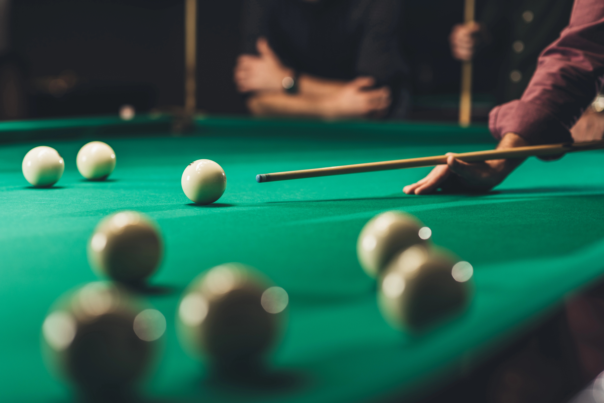 Side view of cropped man playing pool at bar