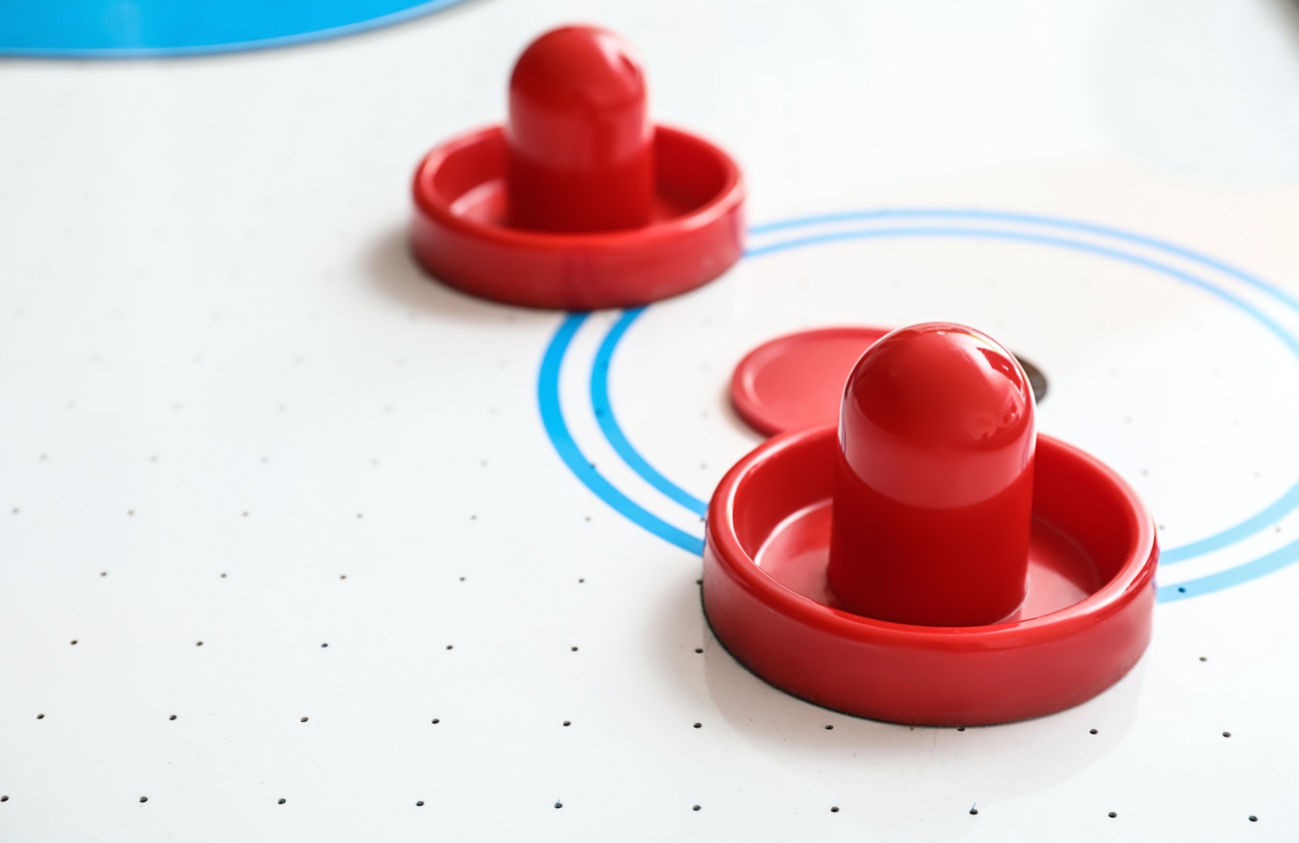 close up of two mallets and a puck on an air hockey table