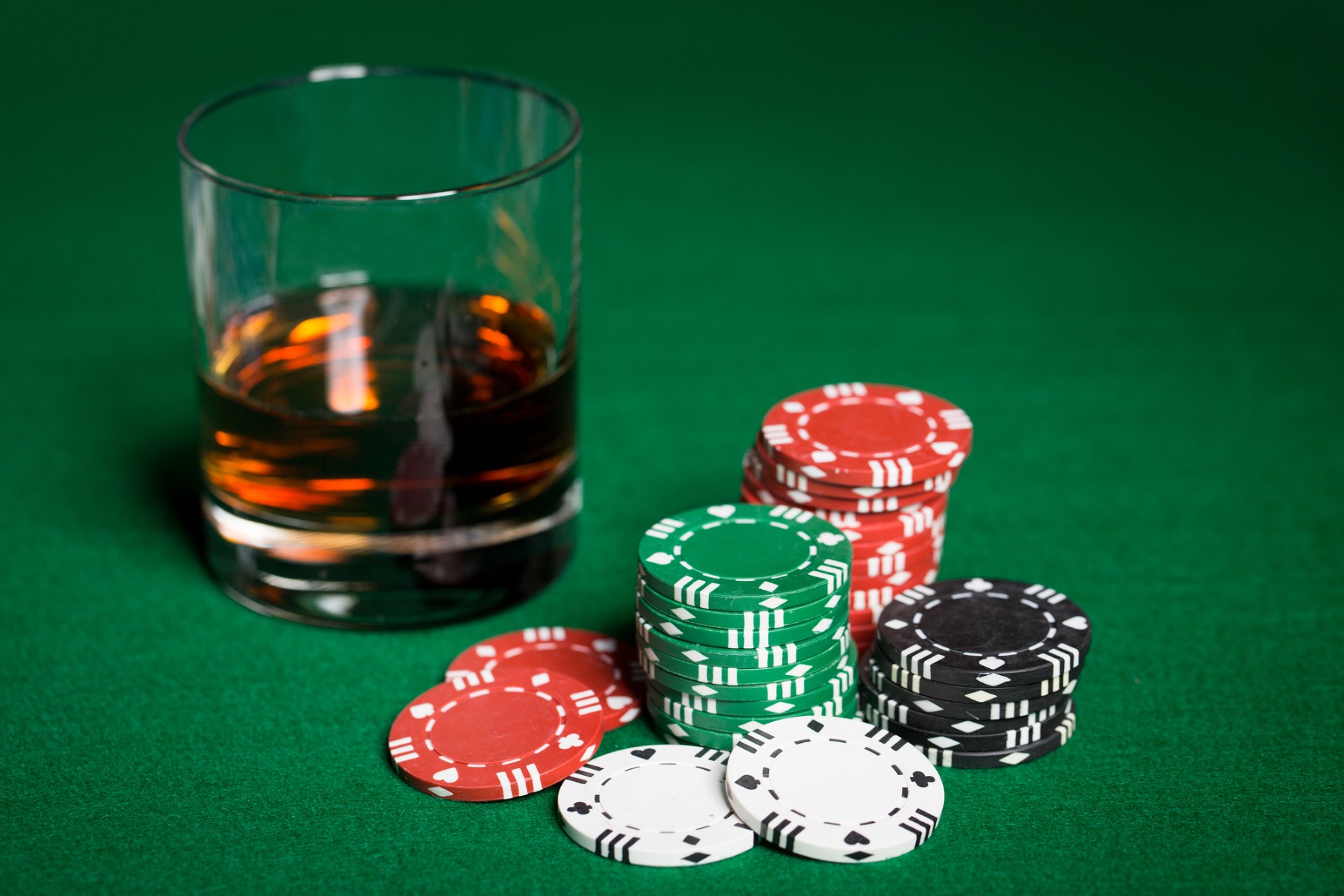 poker chips next to a drink on a poker table